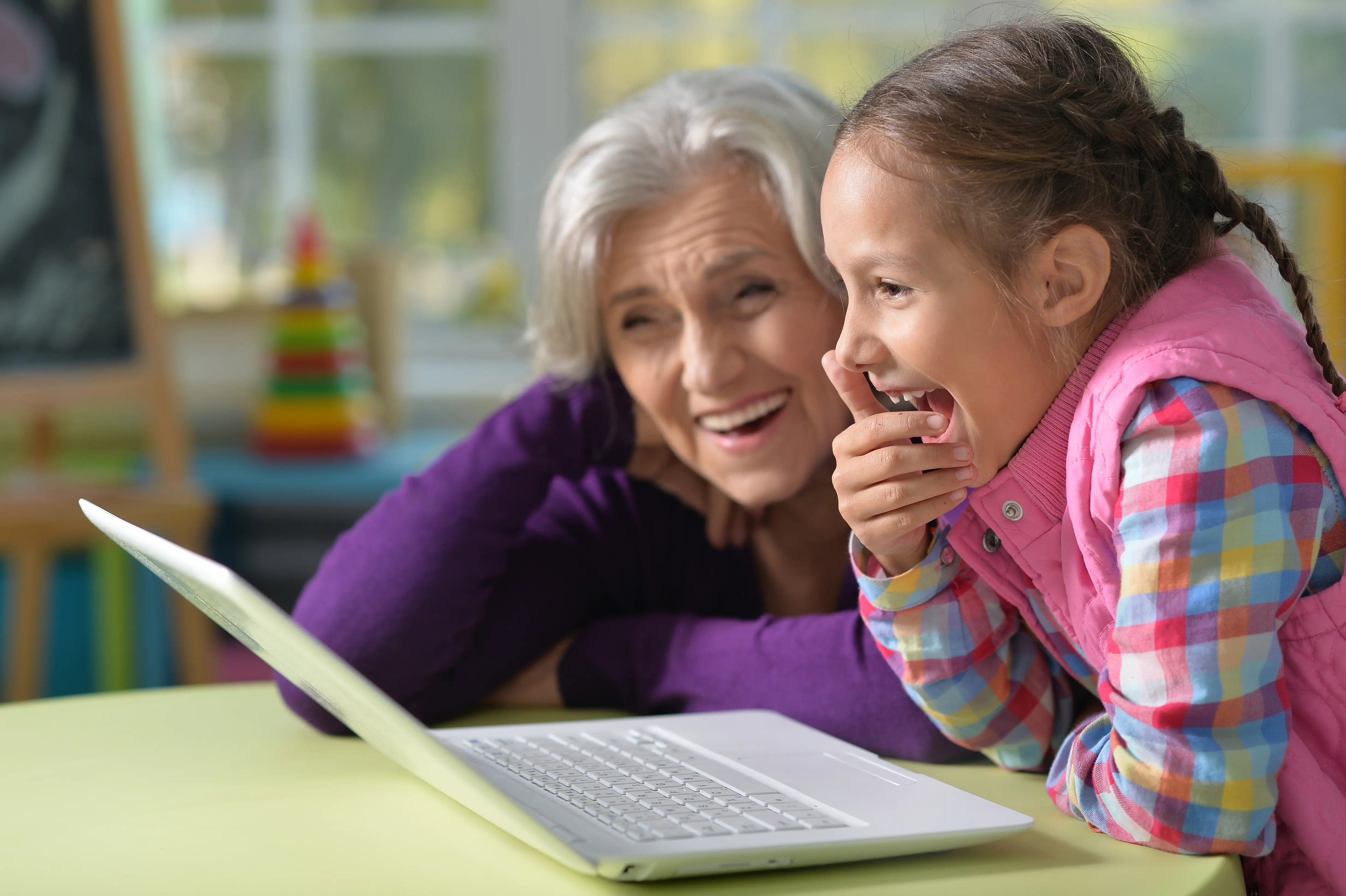 Old lady and a girl at laughing at laptop
