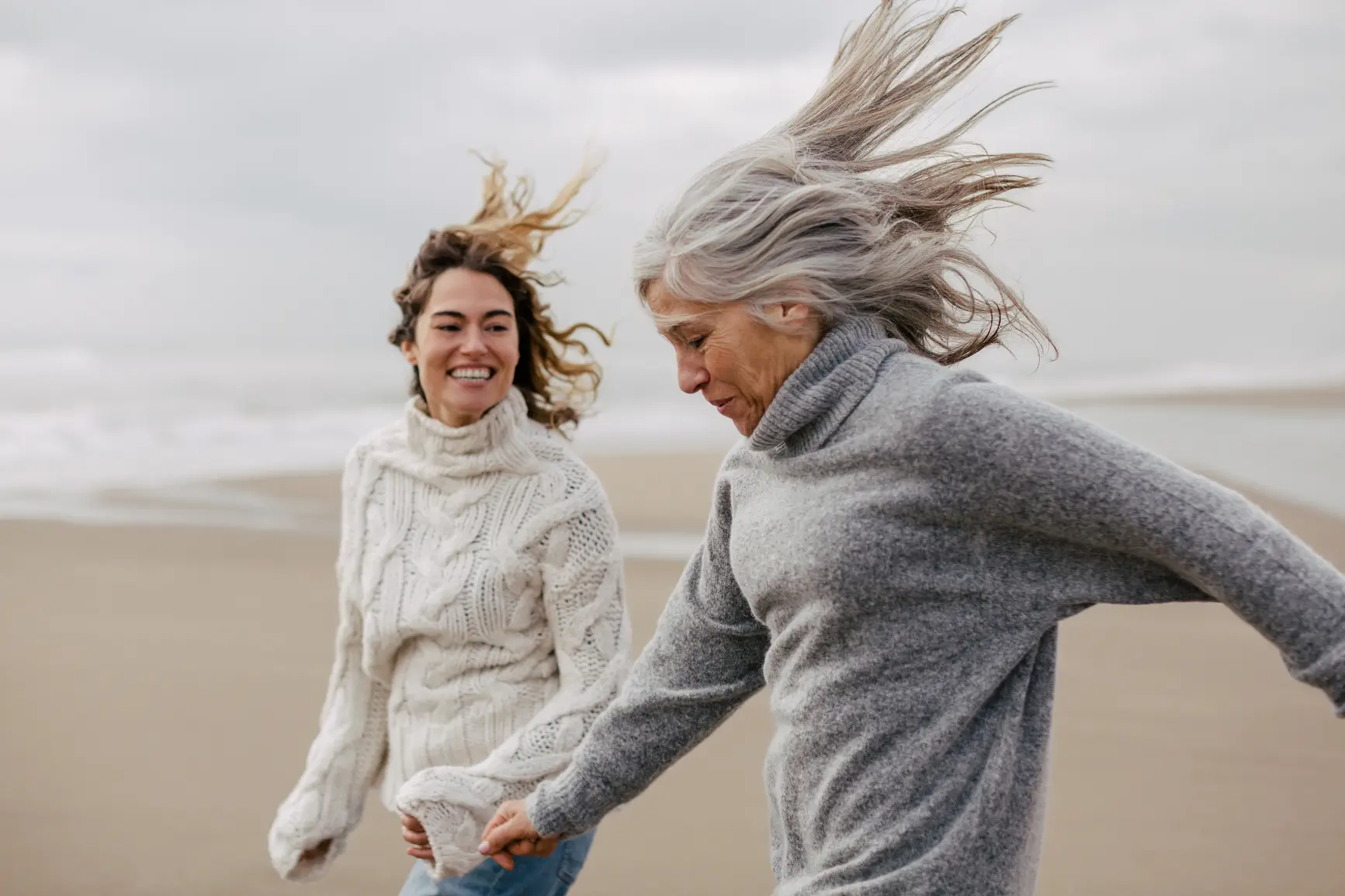 An elderly woman and a young woman walking on the beach